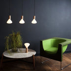 Tapered matte white bulb pendant, oak, three pendants lit above a table in a dark room