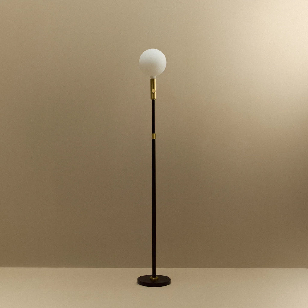 Brass telescopic floor lamp with a globe bulb, unlit