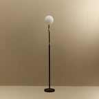 Brass telescopic floor lamp with a globe bulb, unlit