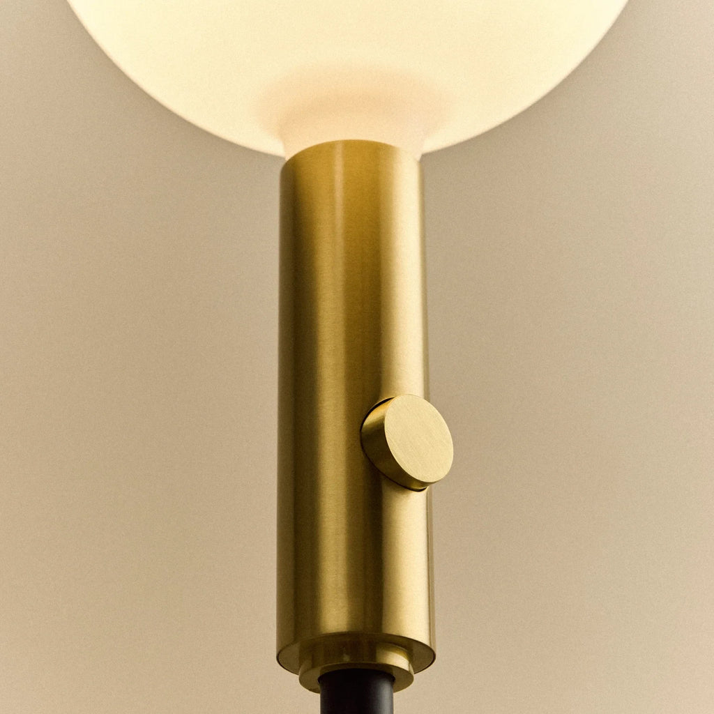 Brass telescopic floor lamp with a globe bulb, close-up of the brass stem and control