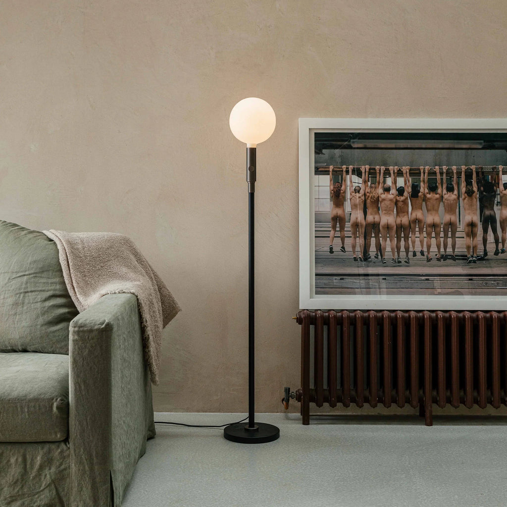 Graphite telescopic floor lamp, beside a sofa and framed art