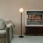Graphite telescopic floor lamp, beside a sofa and framed art