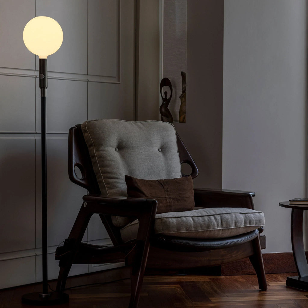 Graphite telescopic floor lamp, beside an armchair