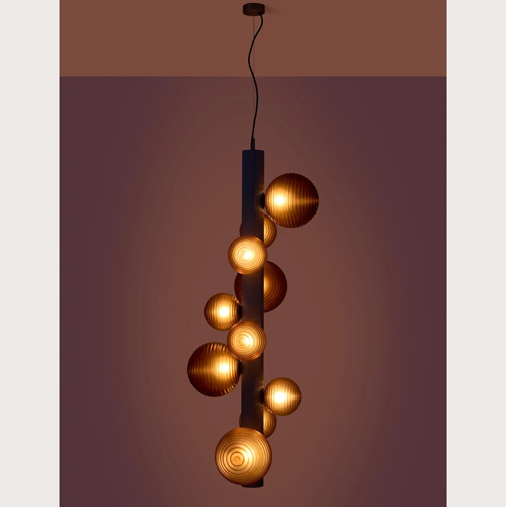 Ten-globe glass tube pendant, lit against a dark wall