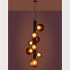 Ten-globe glass tube pendant, lit against a dark wall