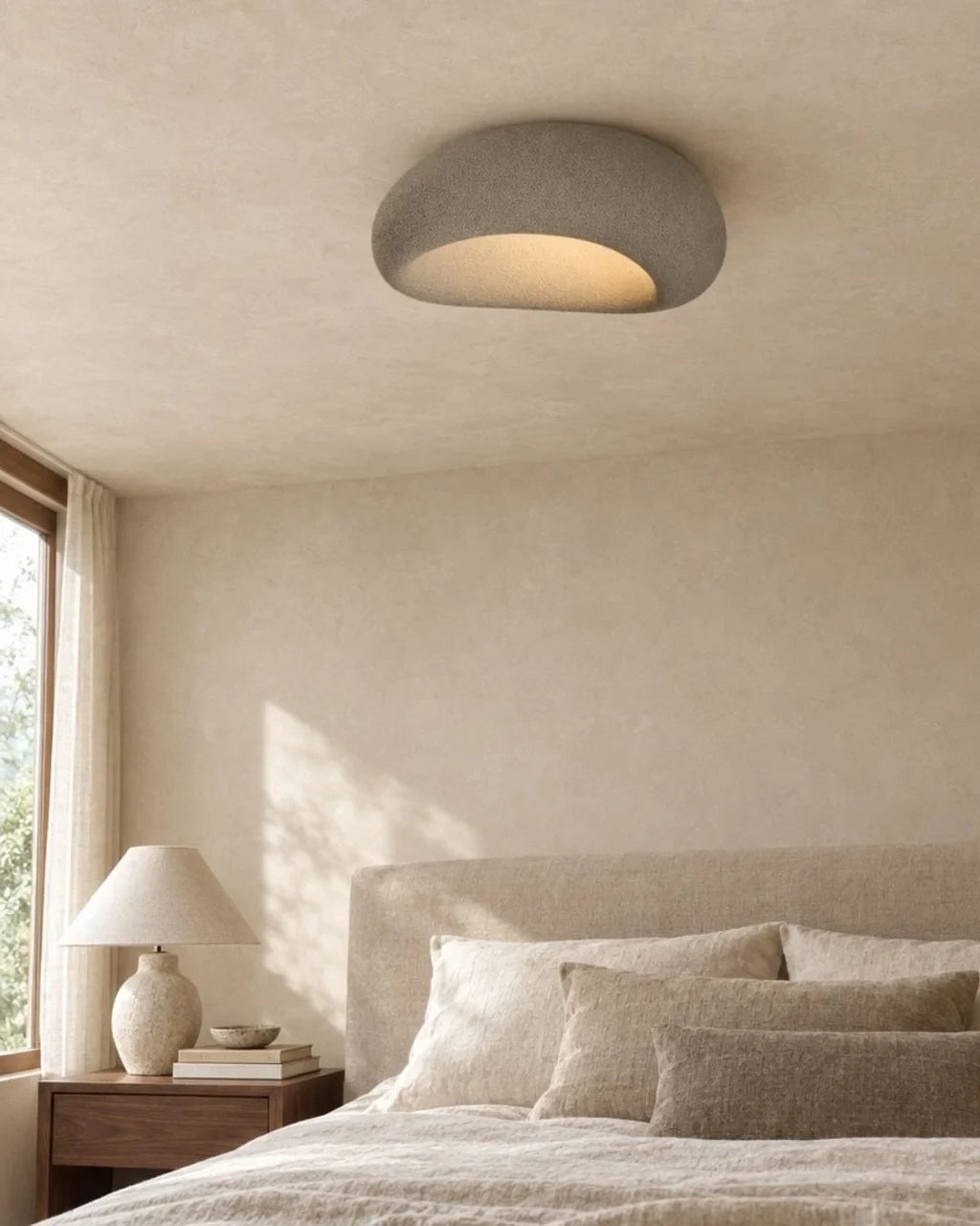 Textured pebble flush ceiling light, in grey, above a bed