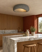 Textured pebble flush ceiling light, in dark grey, above a kitchen island