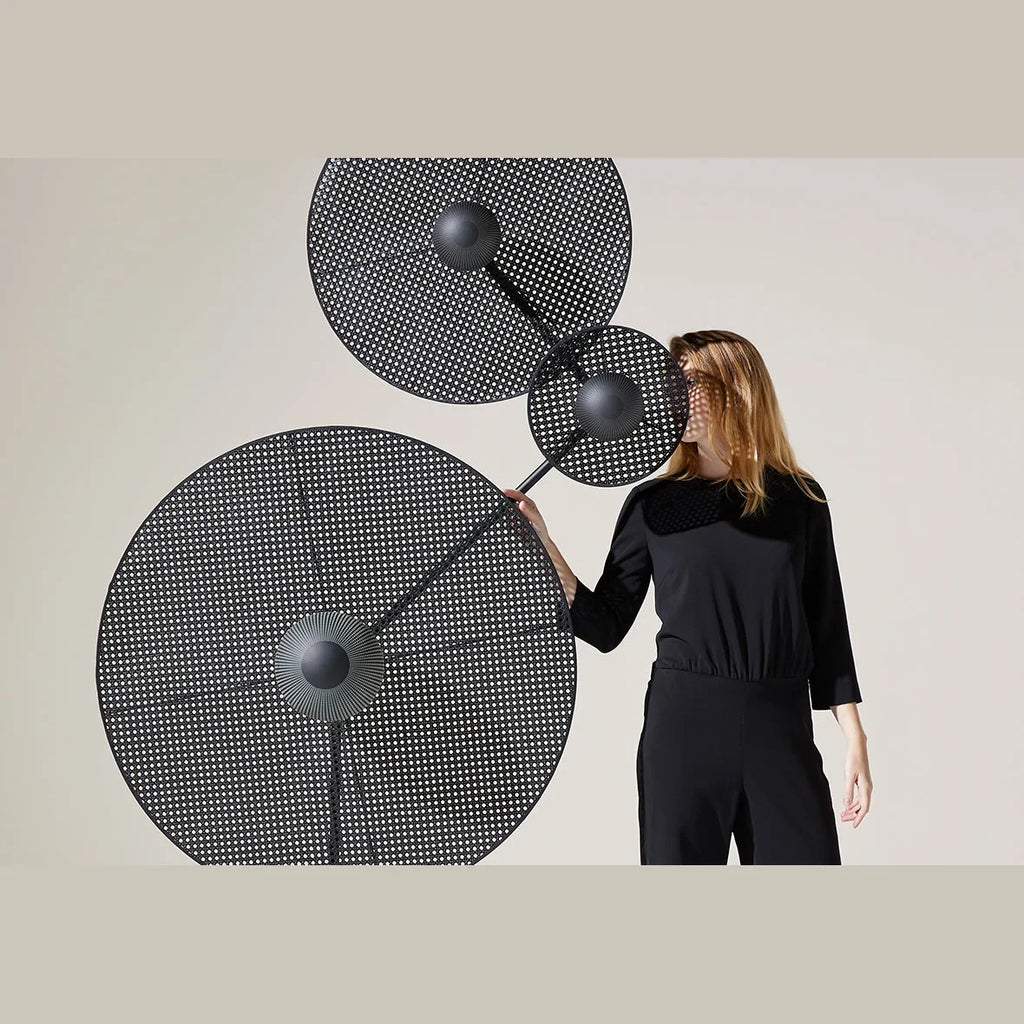 Three-holder floor lamp with angled arm, shown with optional discs (not included), with a person standing behind them