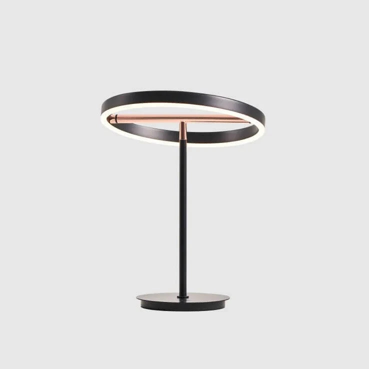 Tilting ring LED table lamp, black and copper, lit, on a pale background