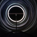 Tilting ring LED table lamp, black and copper, lit ring in a dark setting