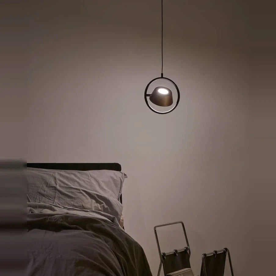 Tilting shade LED pendant in ring frame, beside a bed