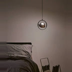 Tilting shade LED pendant in ring frame, beside a bed