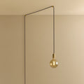 Tinted filament globe plug-in pendant, in brass, routed across the ceiling and down the wall