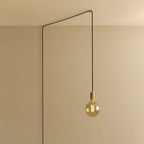 Tinted filament globe plug-in pendant, in brass, routed across the ceiling and down the wall