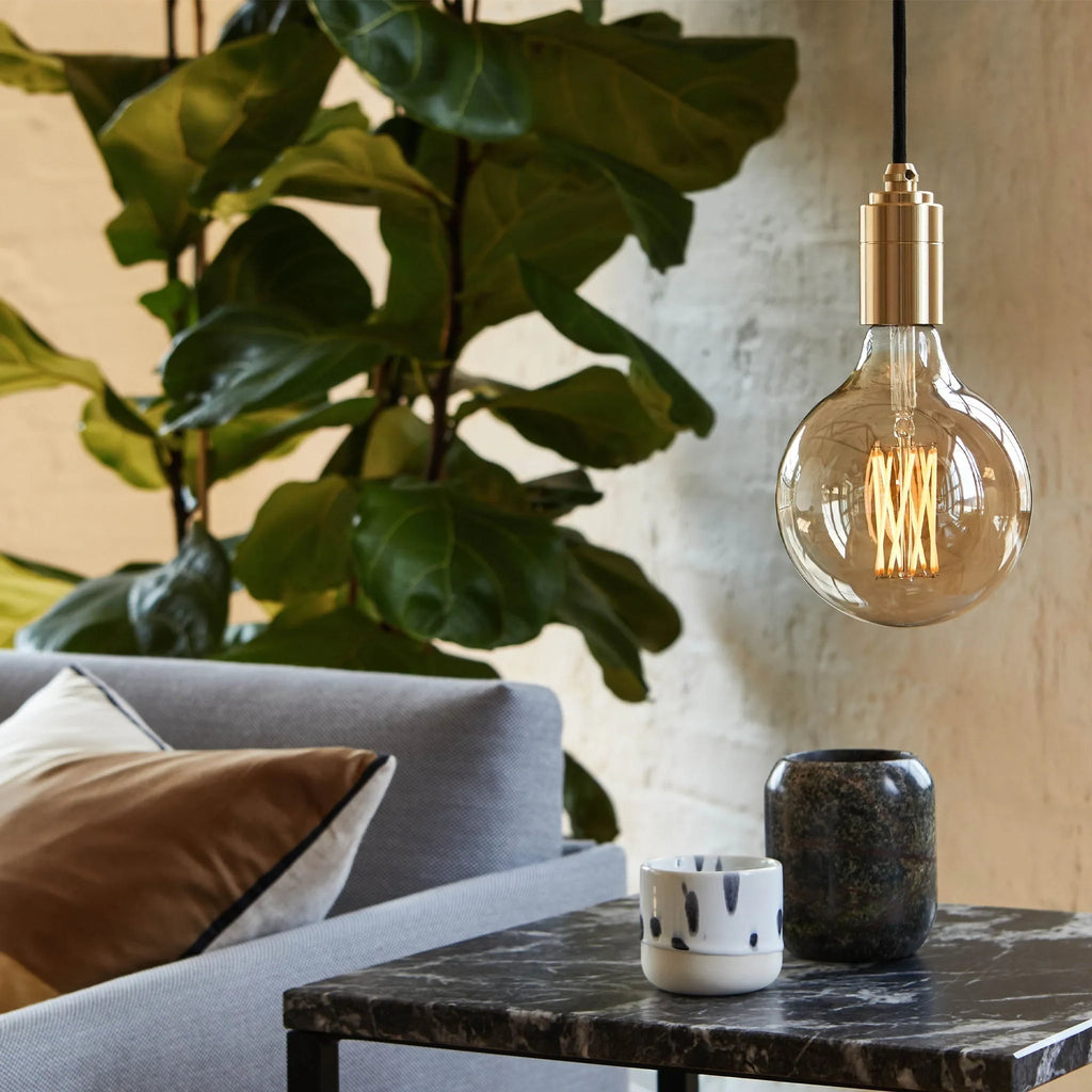 Tinted filament globe plug-in pendant, above a side table by a sofa