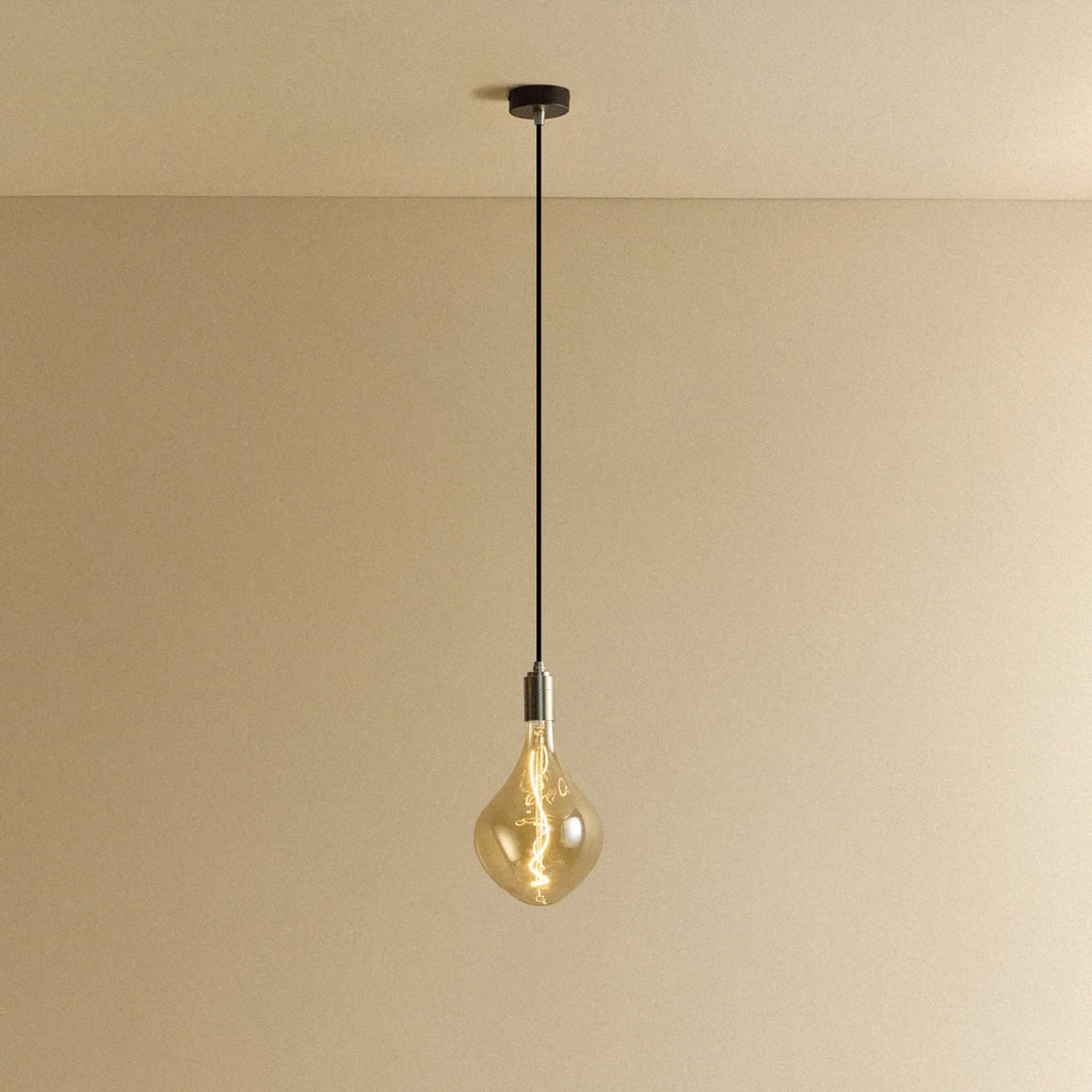 Tinted sculptural glass bulb pendant, stainless steel, against a plain wall
