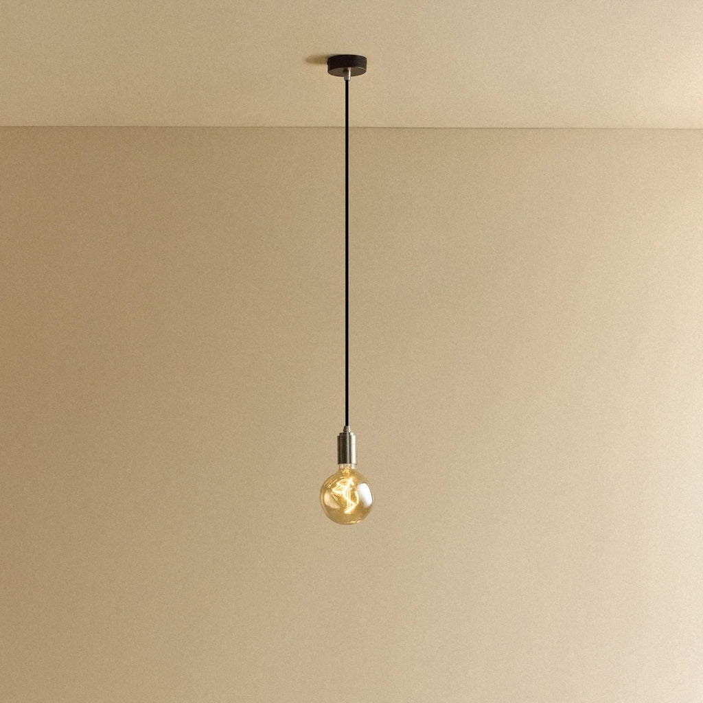 Tinted globe bulb pendant, in stainless steel against a plain wall