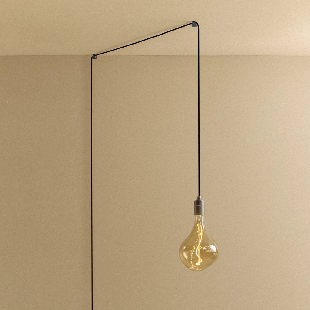 Plug-in pendant with tinted organic bulb, graphite, lit, hung from a wall node