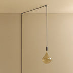 Plug-in pendant with tinted organic bulb, graphite, lit, hung from a wall node, another angle