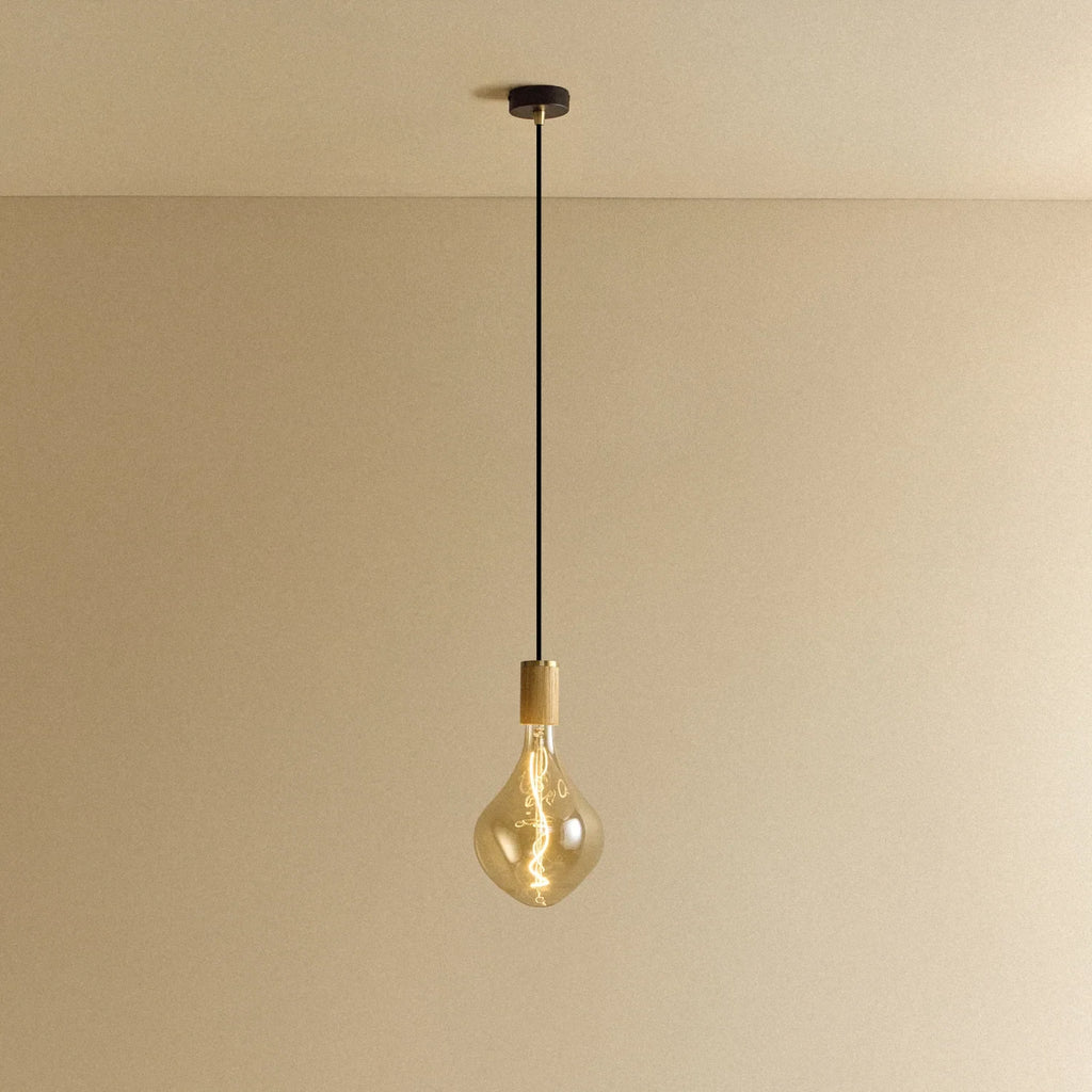 Tinted Sculptural Bulb Pendant, in oak, lit, against a plain wall