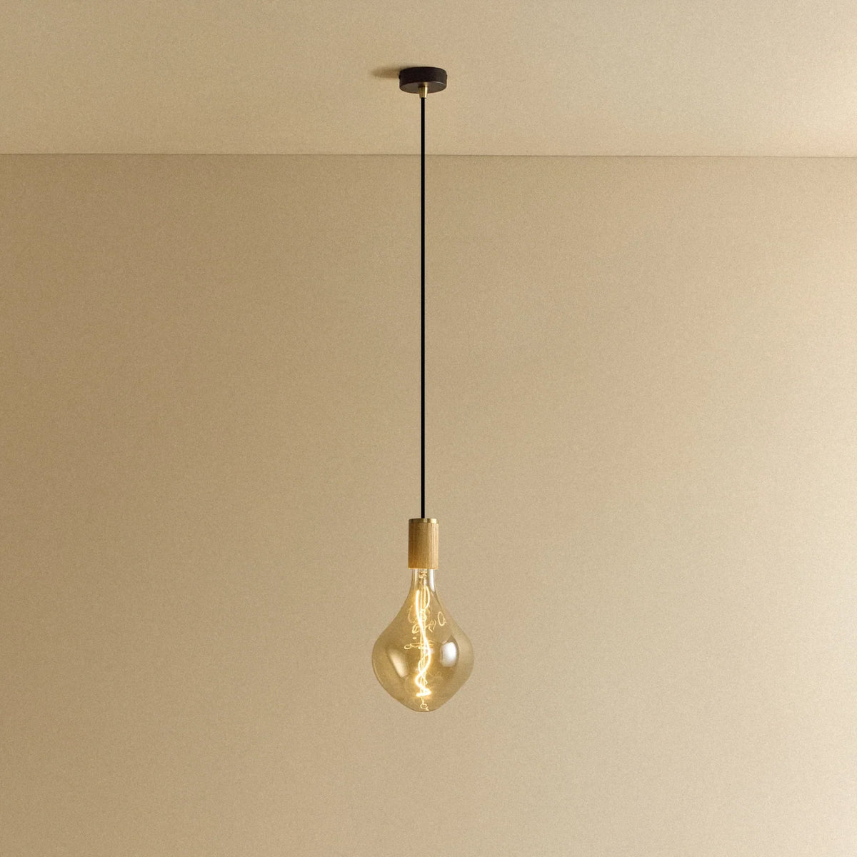 Tinted Sculptural Bulb Pendant, in oak, lit, against a plain wall