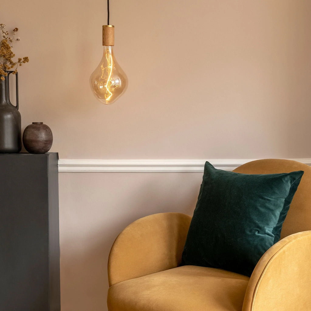 Tinted Sculptural Bulb Pendant, lit beside an armchair in a living room