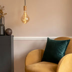 Tinted Sculptural Bulb Pendant, lit beside an armchair in a living room