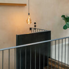Large tinted teardrop bulb pendant, graphite, beside a staircase