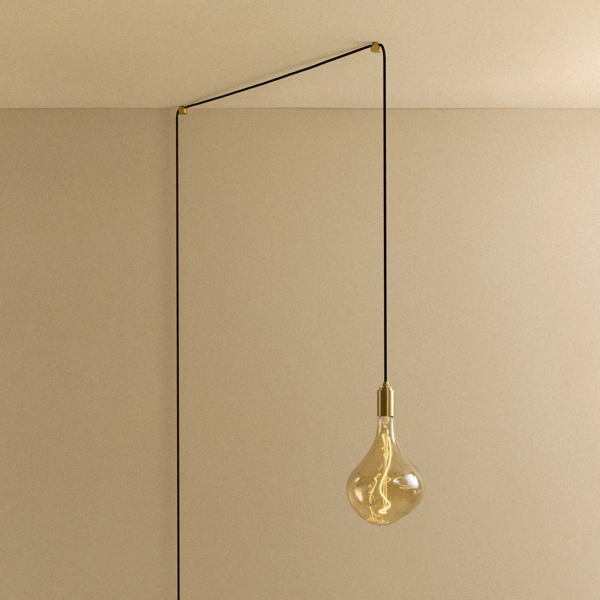 Tinted teardrop bulb plug-in pendant, routed across the ceiling and down the wall