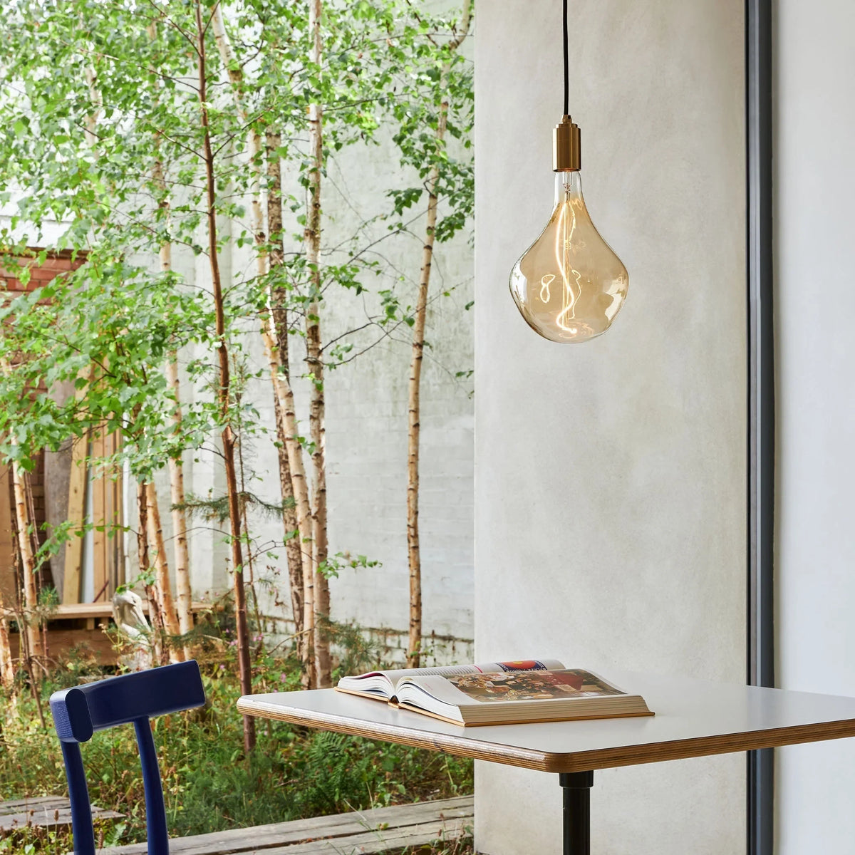 Tinted teardrop bulb plug-in pendant, above a table by a garden window