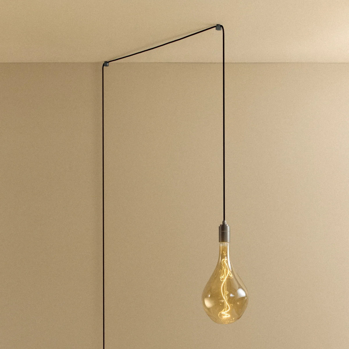 Plug-in pendant with large tinted teardrop bulb, graphite, lit, hung from a wall node