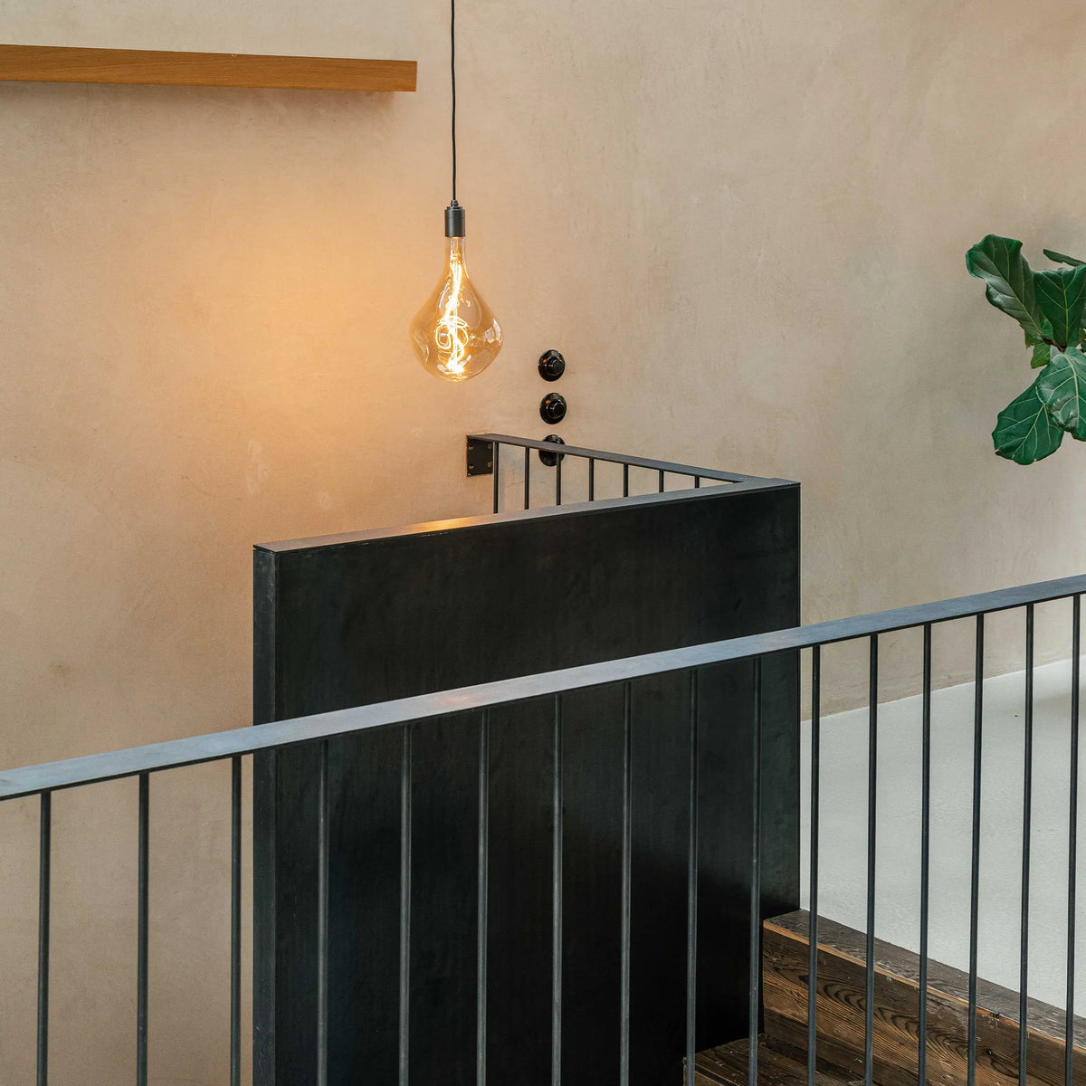 Plug-in pendant with large tinted teardrop bulb, graphite, beside a staircase