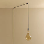 Plug-in pendant with large tinted teardrop bulb, graphite, lit, hung from a wall node, another angle
