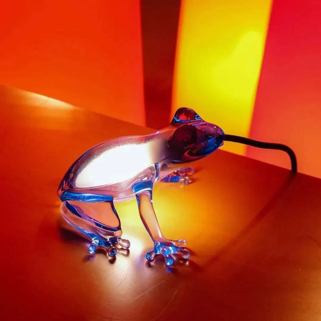 Translucent frog table lamp, in blue on a bright orange surface