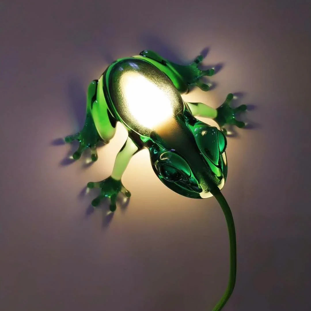 Translucent frog table lamp, in green, glowing against a wall