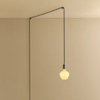 Plug-in pendant with a trapezoid matte white glass bulb, graphite, lit, hung from a ceiling corner