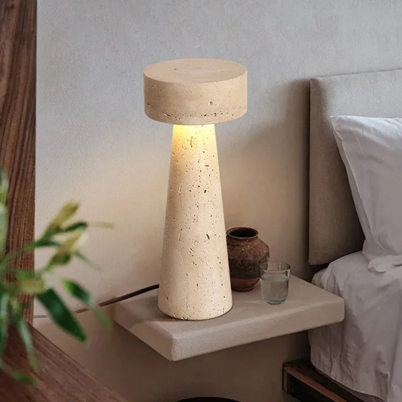 Travertine table lamp glowing on a floating bedside shelf