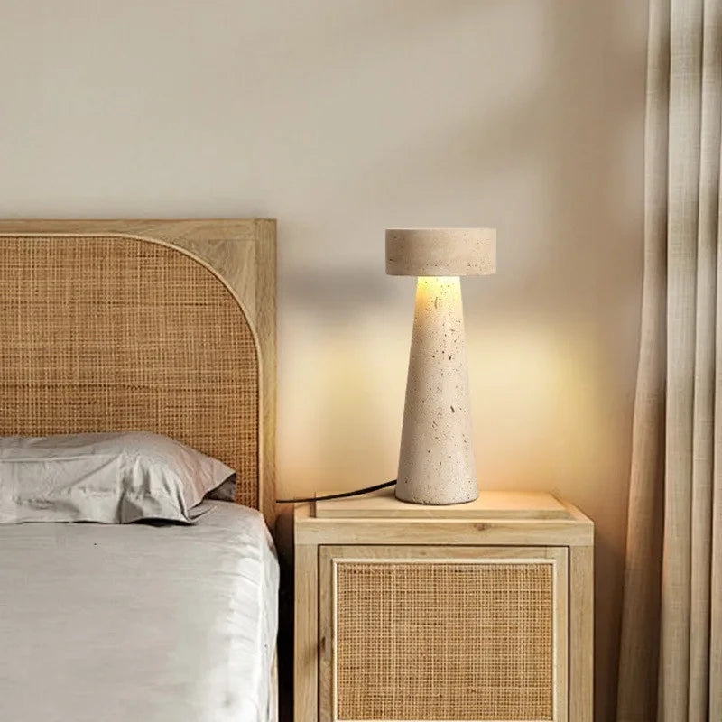 Travertine table lamp on a rattan bedside cabinet in a calm bedroom