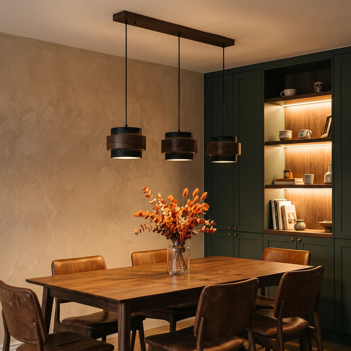 Three black travertine and walnut drum pendants over a dining table