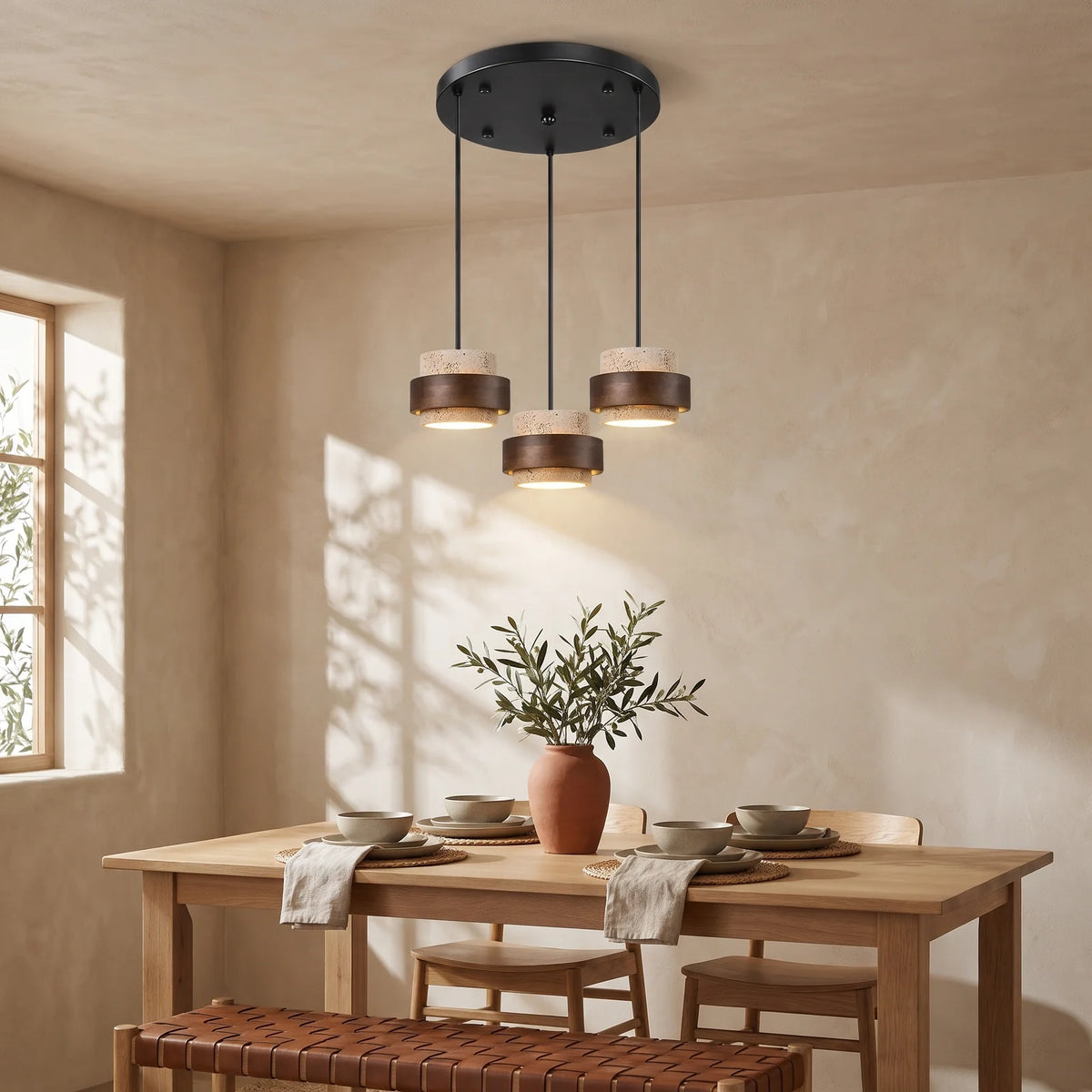 Three beige travertine and walnut drum pendants on a round canopy over a dining table