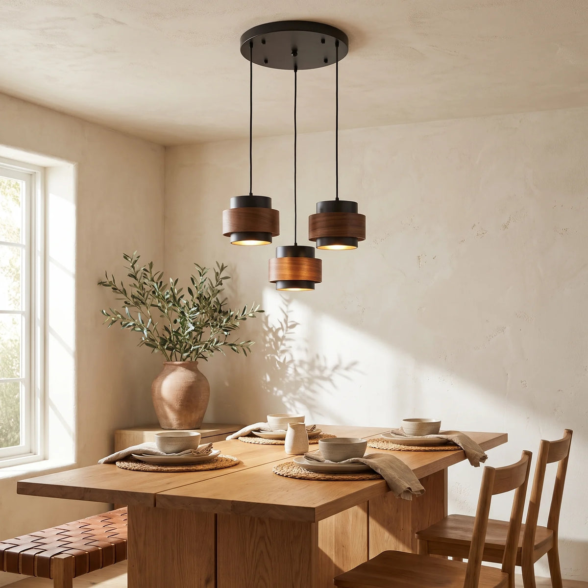 Three black travertine and walnut drum pendants on a round canopy over a dining table