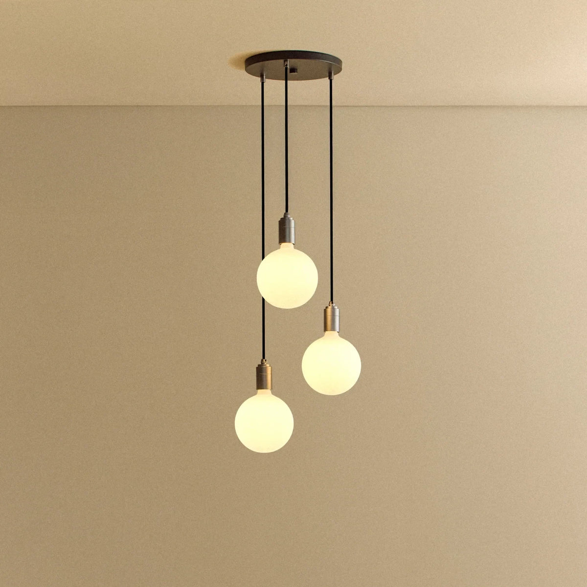 Triple Opal Sphere Cluster Pendant, in graphite, lit, against a plain wall