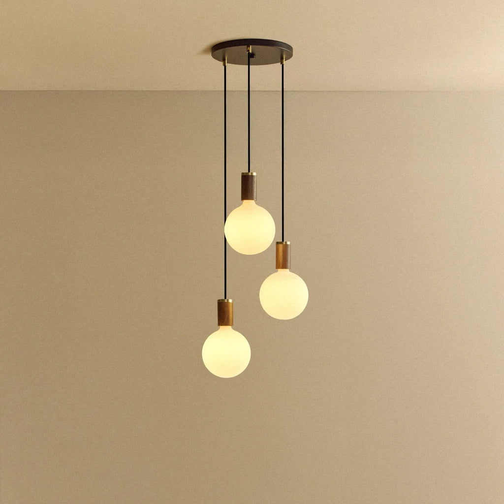 Triple Opal Sphere Cluster Pendant, in walnut, lit, against a plain wall