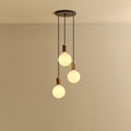 Triple Opal Sphere Cluster Pendant, in walnut, lit, against a plain wall