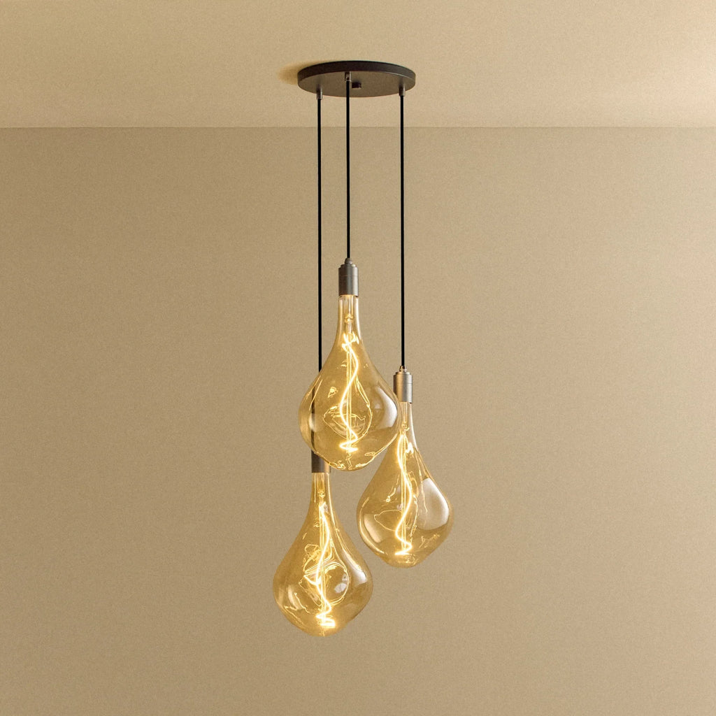 Triple Tall Tinted Bulb Cluster Pendant, in graphite, lit, against a plain wall