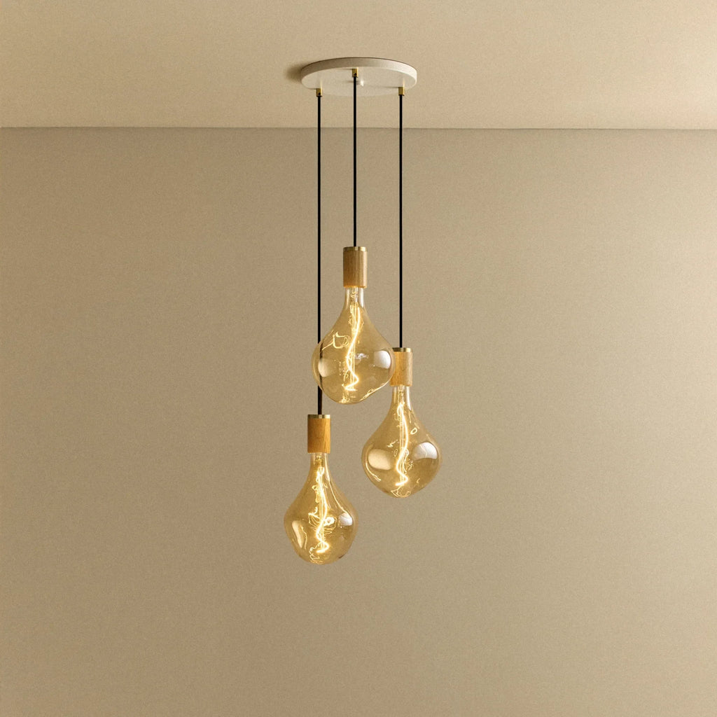 Triple Tinted Bulb Cluster Pendant, in oak, lit, against a plain wall
