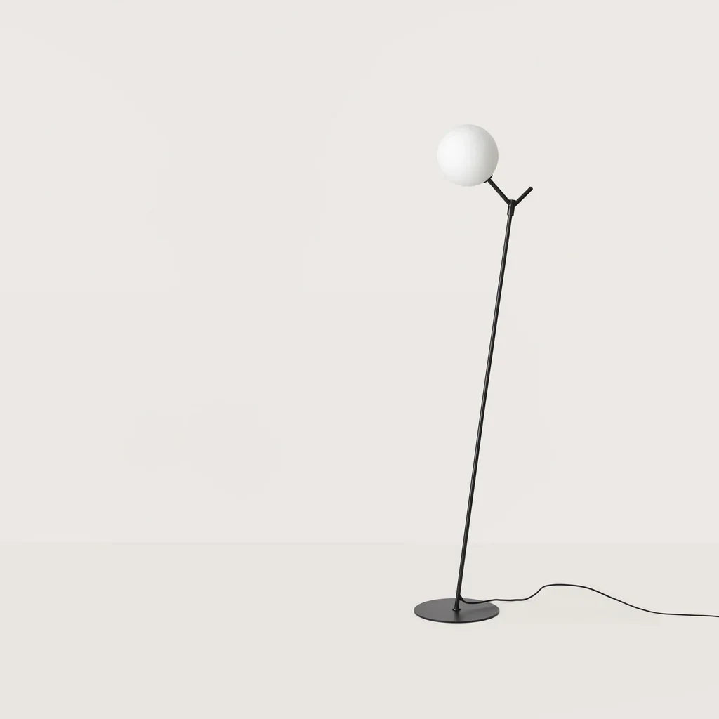 Twig branch floor lamp with opal glass globe, in matte black, on a plain background