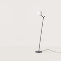 Twig branch floor lamp with opal glass globe, in matte black, on a plain background