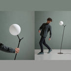 Twig branch floor lamp with opal glass globe, with a person beside it