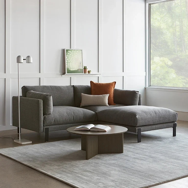 Twin-head adjustable floor lamp with a marble base, in white beside a sofa in a living room